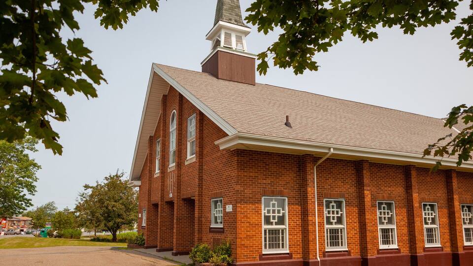 A brick church with a steeple and a cross on top.