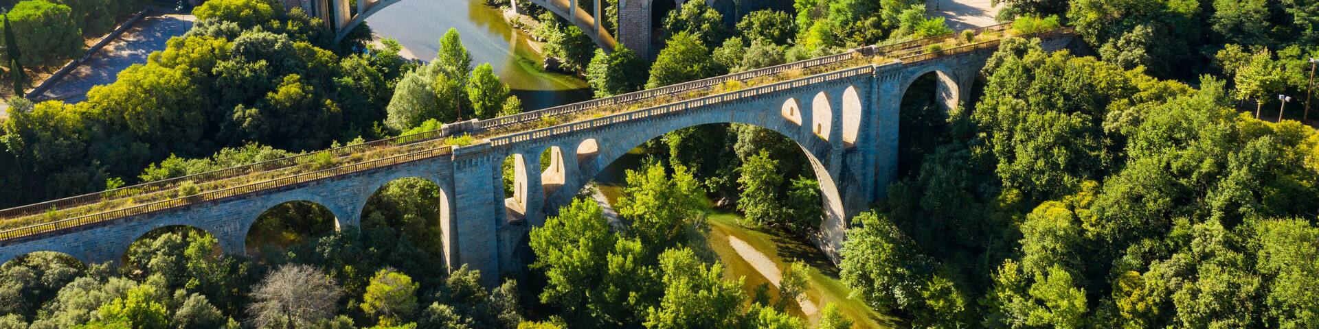 General view from drone of Ceret town on banks of river Tech in foothills of Pyrenees mountains in summer, France..