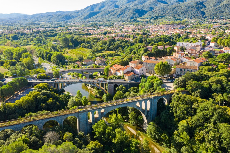 General view from drone of Ceret town on banks of river Tech in foothills of Pyrenees mountains in summer, France..