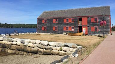 A wooden building with red shutters by a lake.