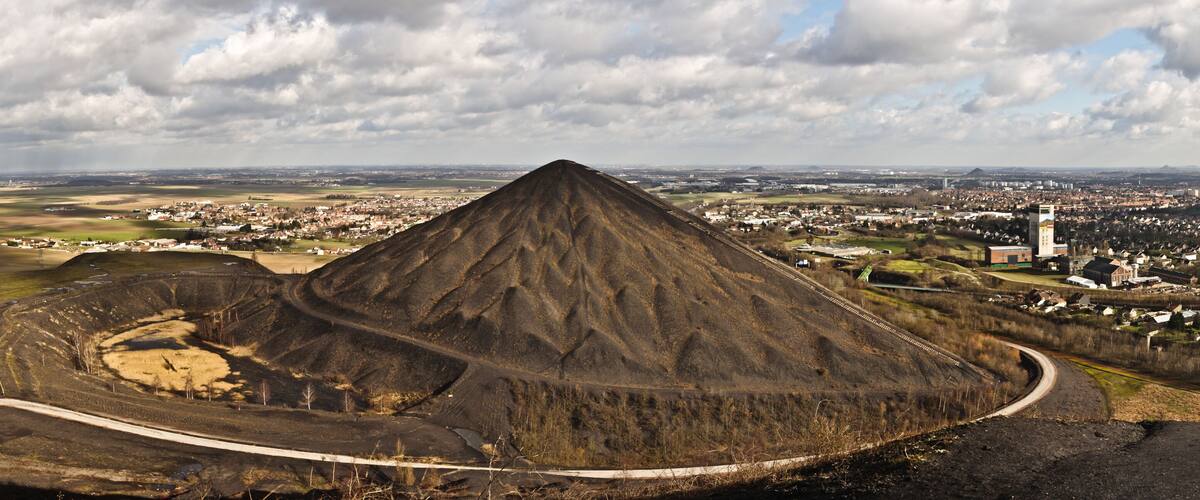 A large, conical hill with a town in the background.