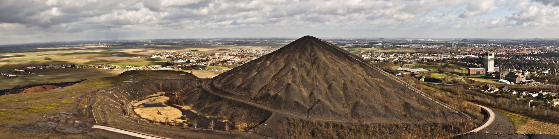 A large, conical hill with a town in the background.