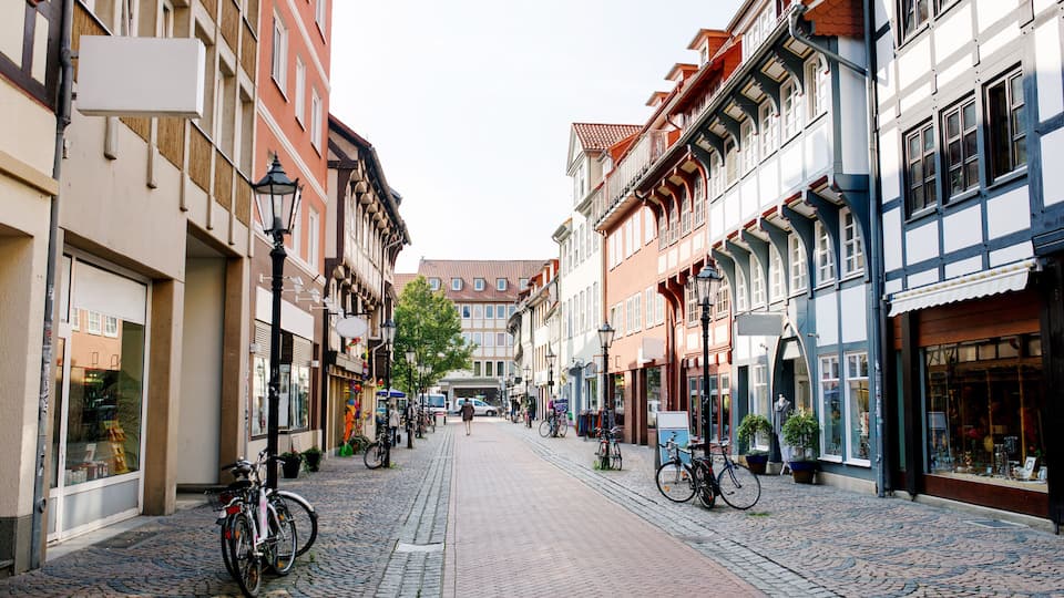 A cobblestone street lined with historic buildings, bicycles parked along the sides, and a clear sky.