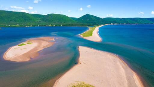 Sandy beach backdropped by green mountains