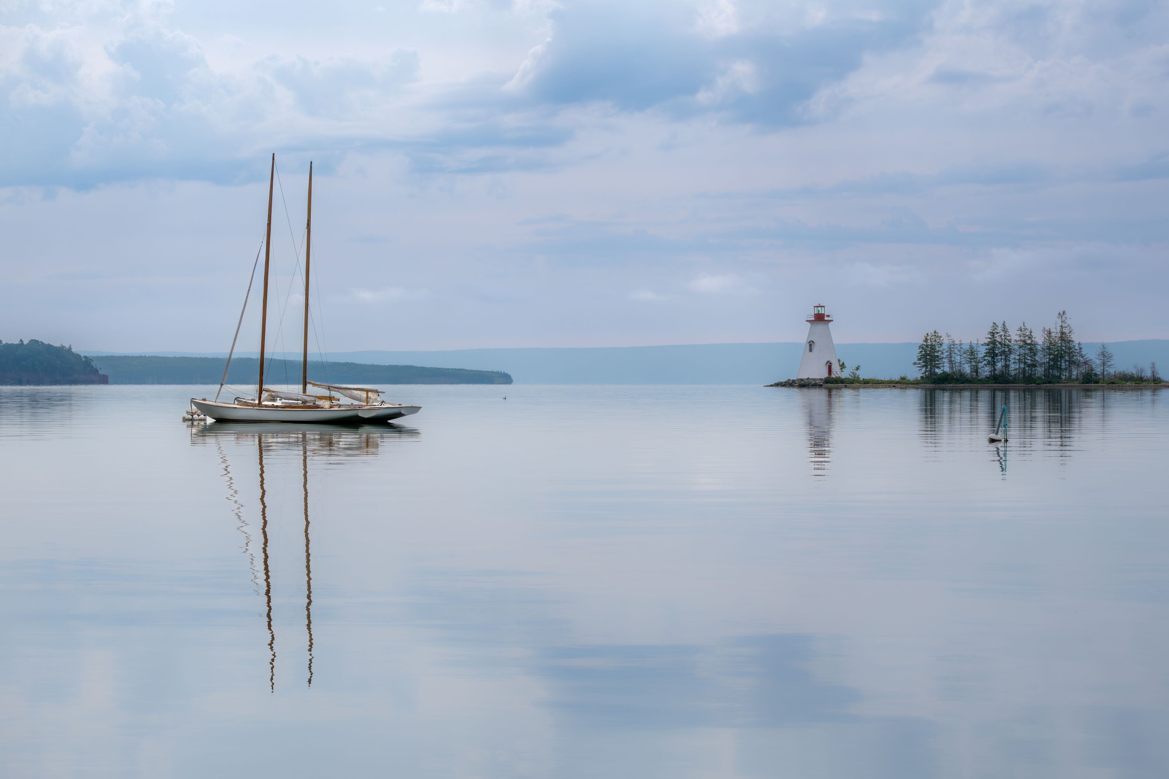 Two moored sailboats and Kidston Island Lighthouse in Baddeck, Nova Scotia, Canada