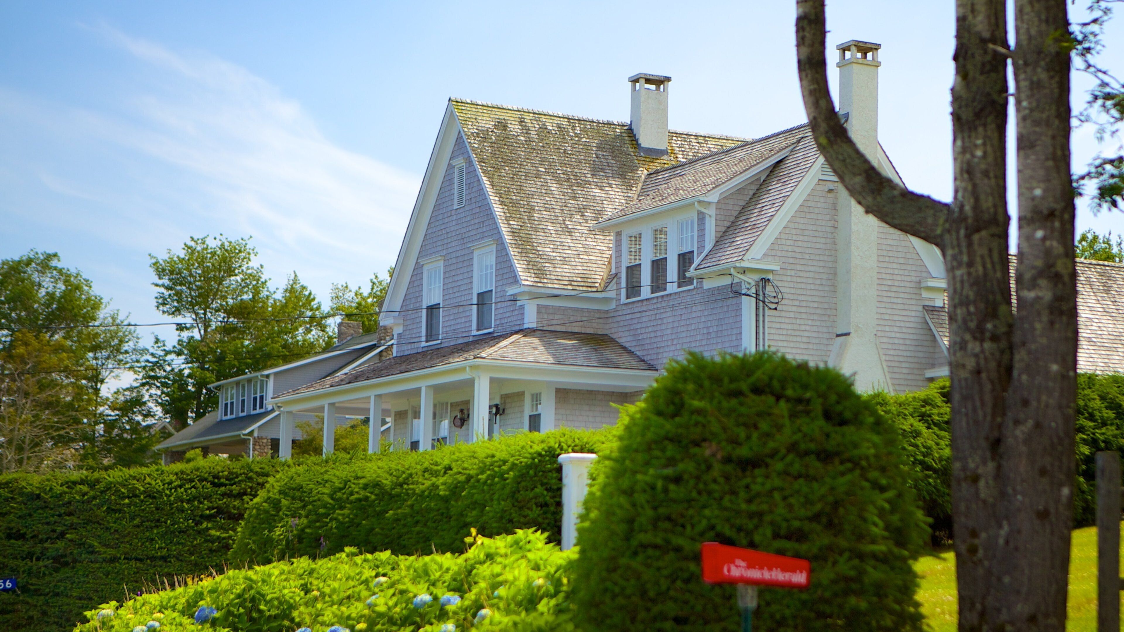 A large, two-story house with a steeply pitched roof and a chimney.