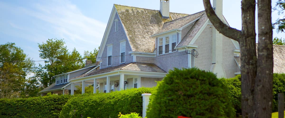A large, two-story house with a steeply pitched roof and a chimney.