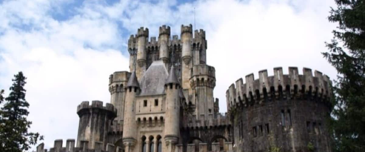 A historic castle with multiple towers, a large arched entrance, and a sign indicating a no parking zone.