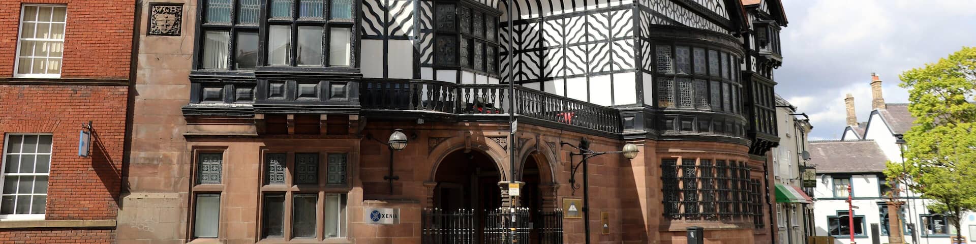 A Tudor-style building with black and white timber framing, a brick facade, and a prominent chimney.