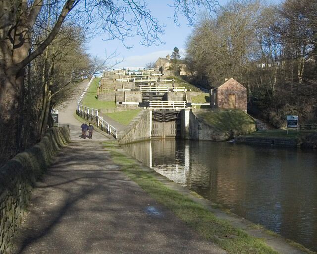 A canal with a lock system, a stone wall, and a small brick building.