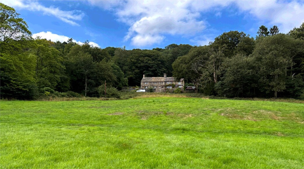 A country house rests in the shade of late summer trees, fields aglow with fading green, under a sky of gentle drift. Harden, Bingley, UK.