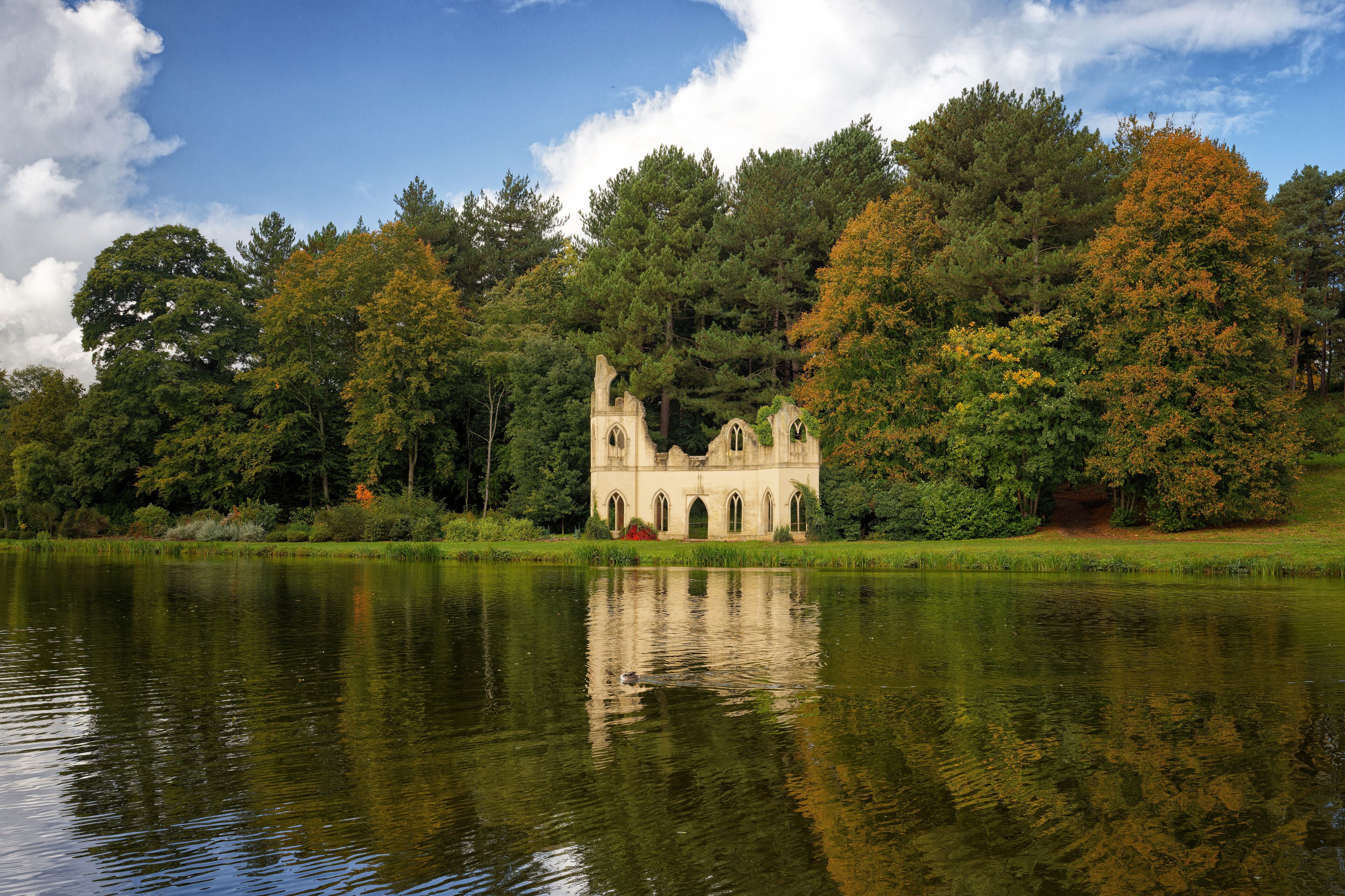 Reflections of the folly in the serpentine lake at Painshill Park in Cobham Surrey England Uk