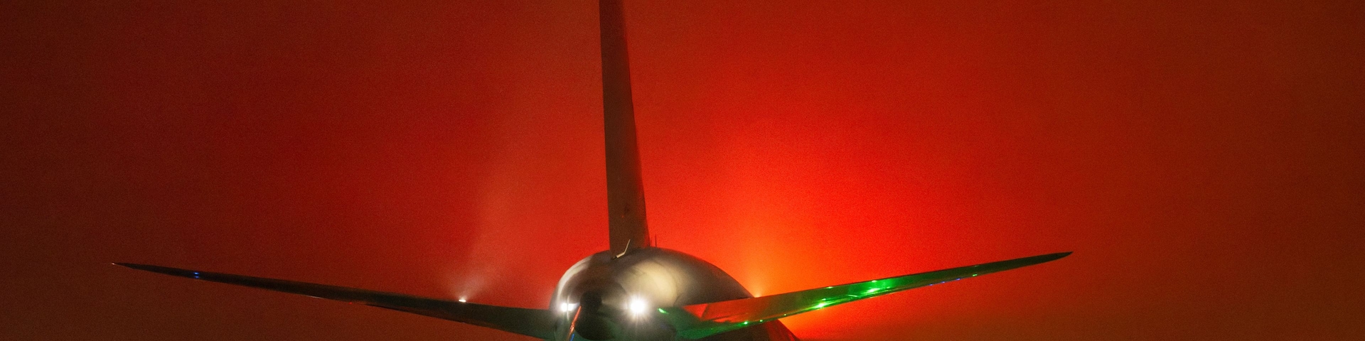 Un avión en la plataforma de vuelo durante la noche con luces de colores.