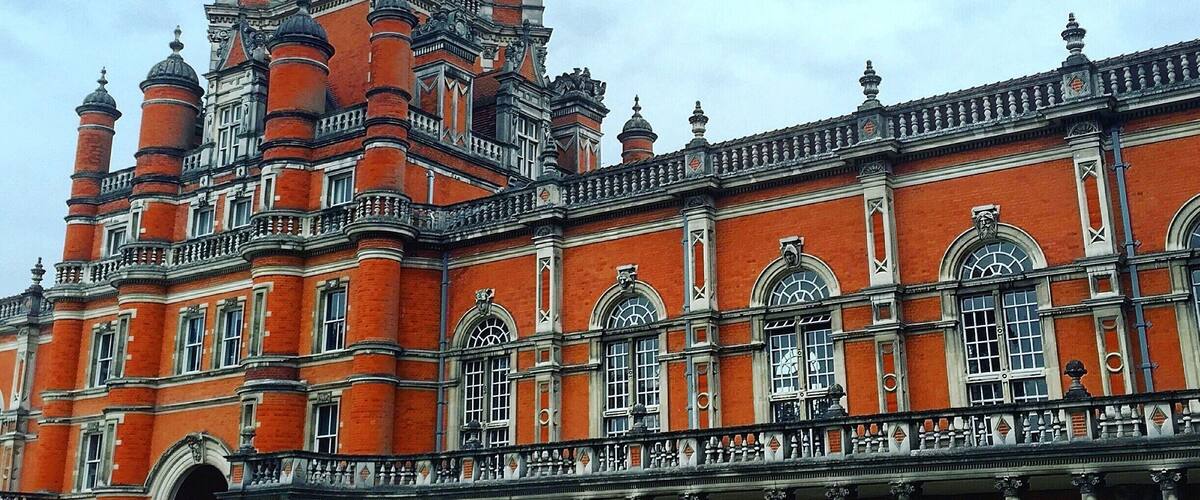 A large red brick building with ornate architecture, including a clock tower and columns.