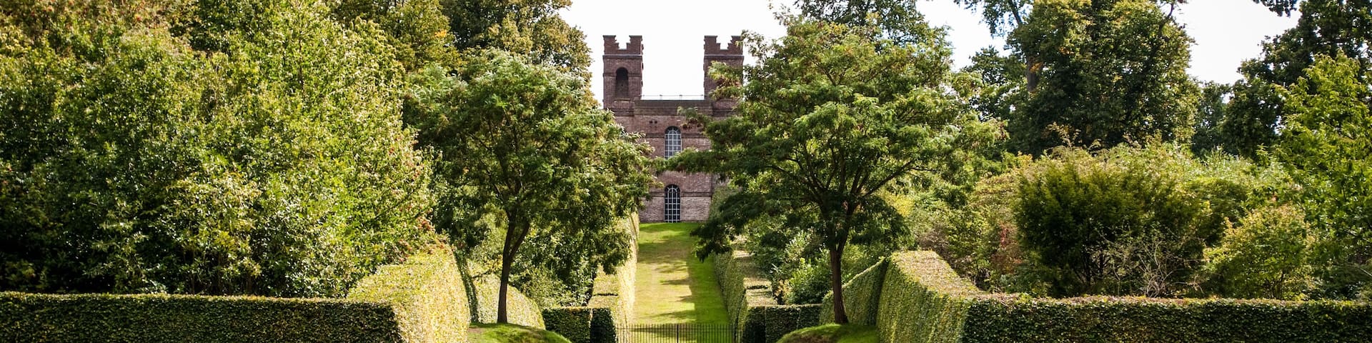 Family having picnic with Belvedere Tower in distance, Claremont Landscape Garden, Esher, Surrey, UK