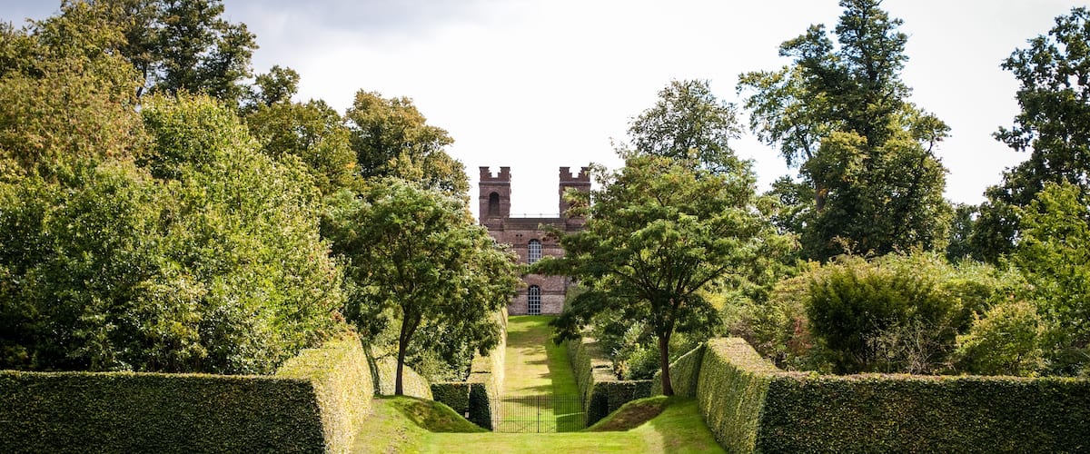 A castle surrounded by neatly trimmed hedges and trees.