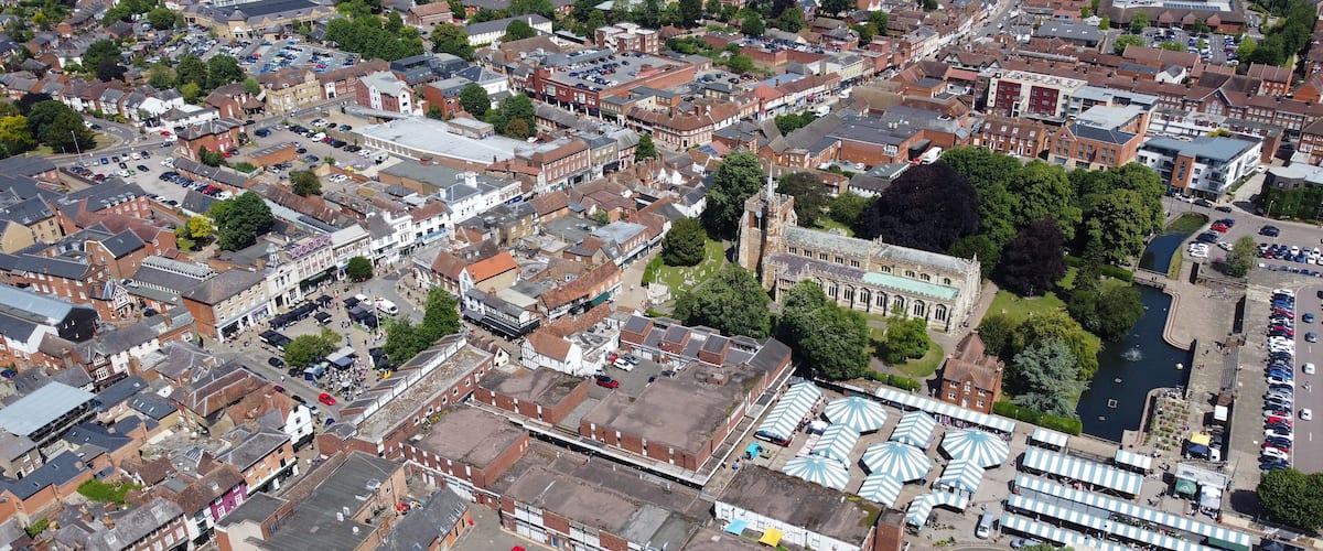 An aerial view of a historic town with narrow streets, a prominent church, and a river.