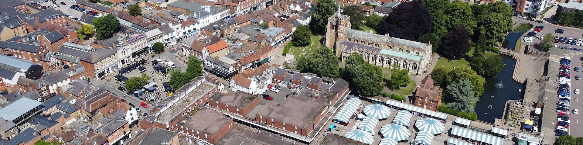 An aerial view of a historic town with narrow streets, a prominent church, and a river.