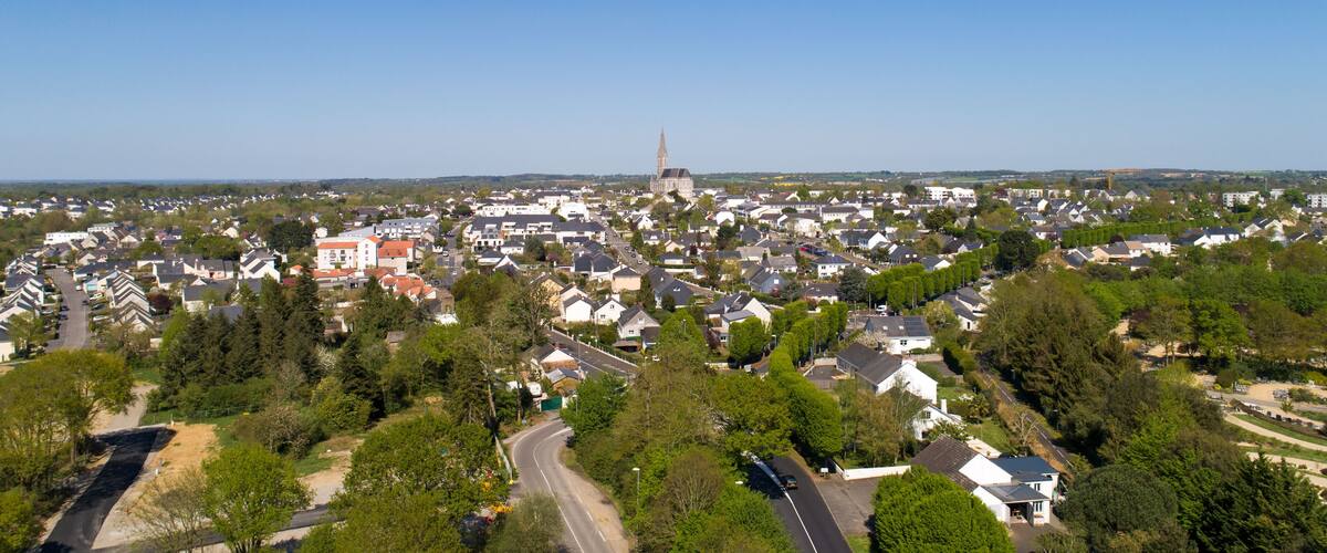 A town with a prominent church spire, surrounded by residential houses and greenery.