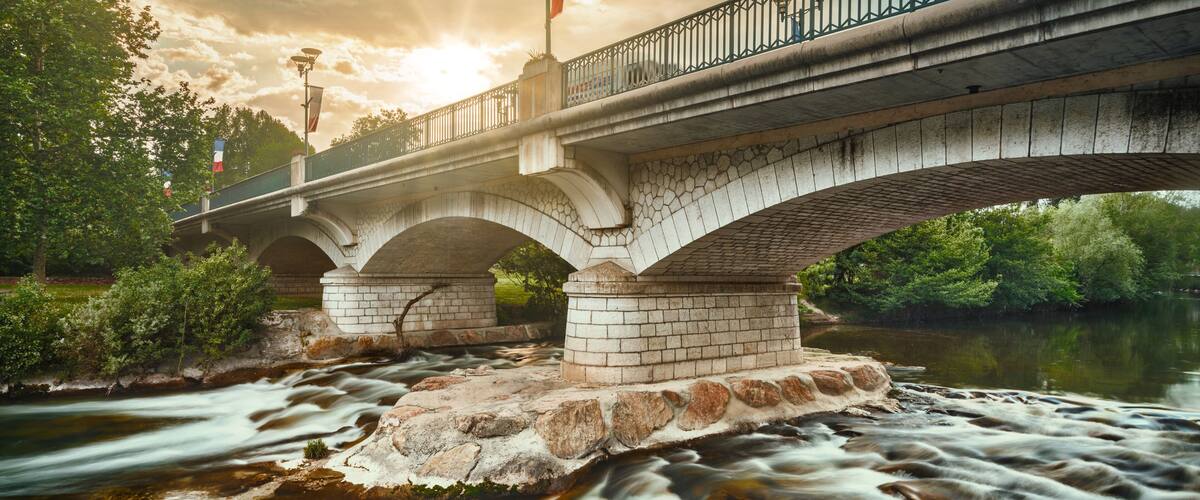 A stone bridge with arches over a flowing river.