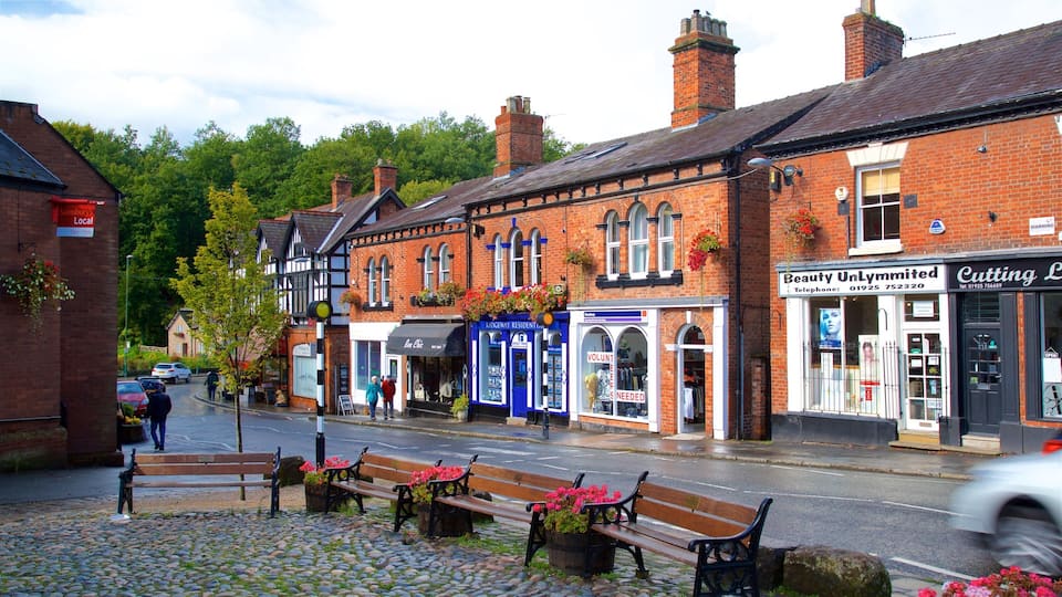 A cobblestone street with benches and flower boxes, shops, and a sign for 'Beauty UnLymmitied'.