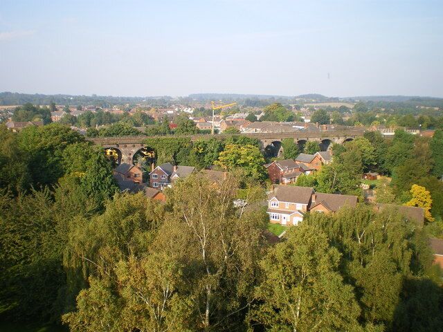 A residential area with houses, trees, and a bridge in the background.