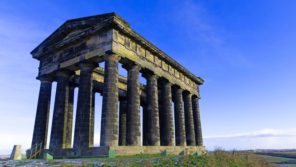 A classical structure with columns and a pediment, set against a clear sky.