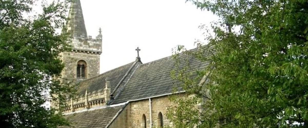 A historic church with a tall spire and a graveyard in front.