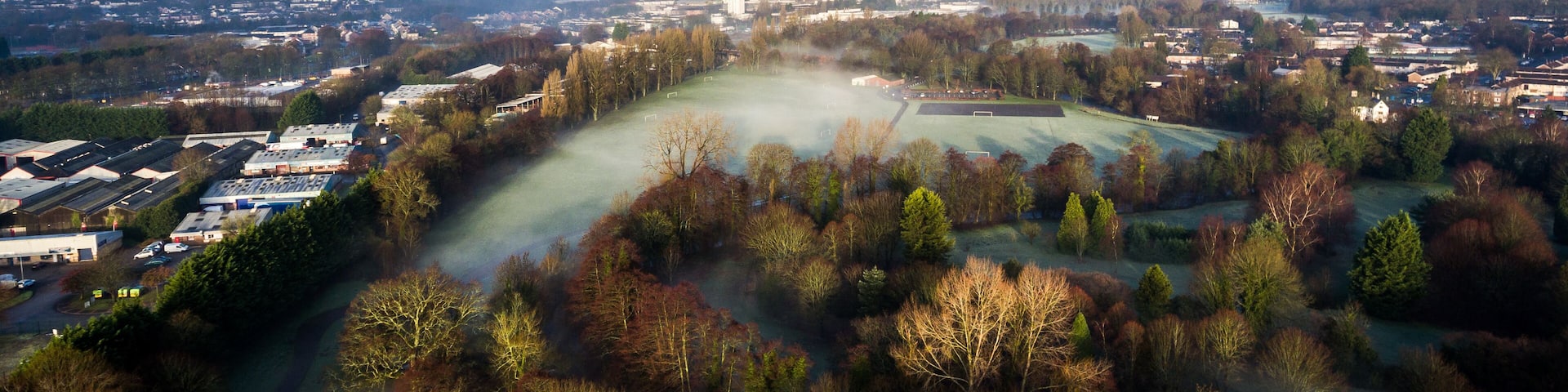 A panoramic view of a town with a river, industrial buildings, and a large open field.