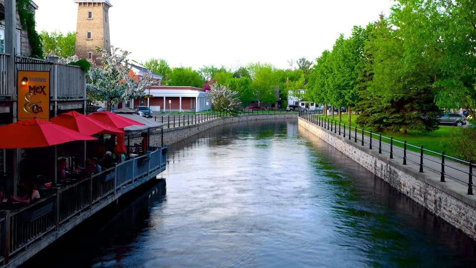 A canal with a restaurant on the left and a bridge in the background.