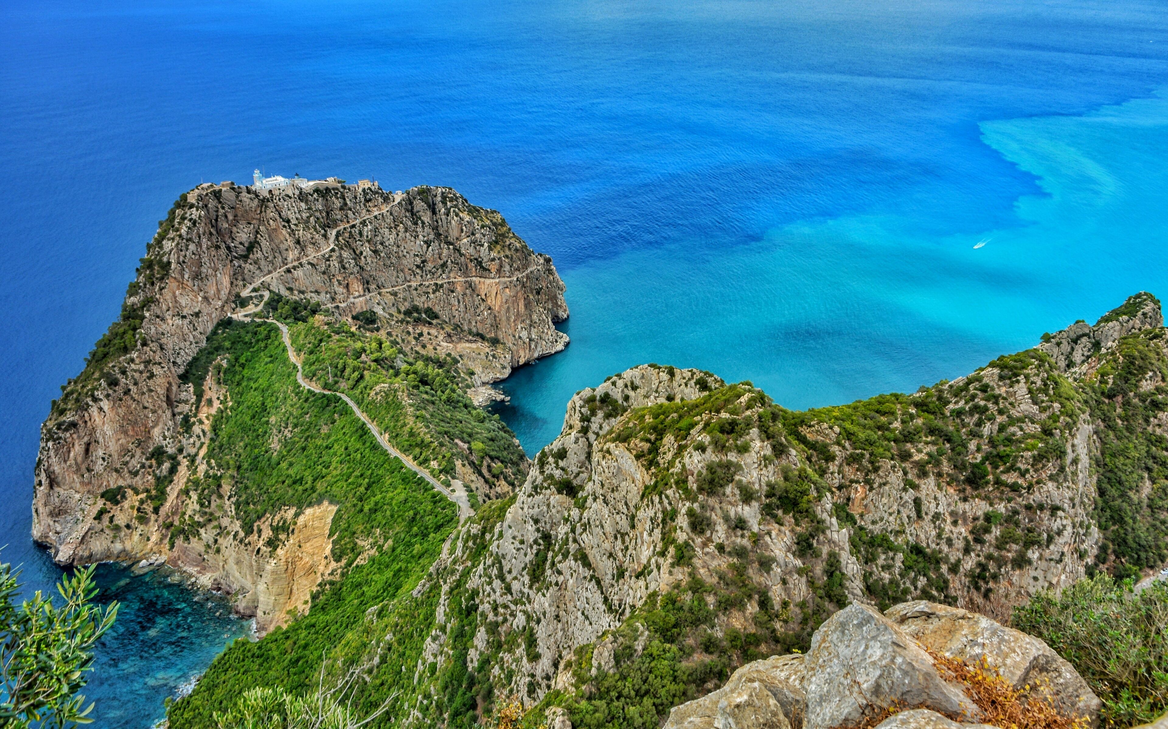 A coastal landscape with rugged cliffs, a winding path, and a lighthouse.