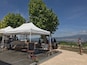 A wine tasting event with white tents and a chalkboard menu under a large tree.