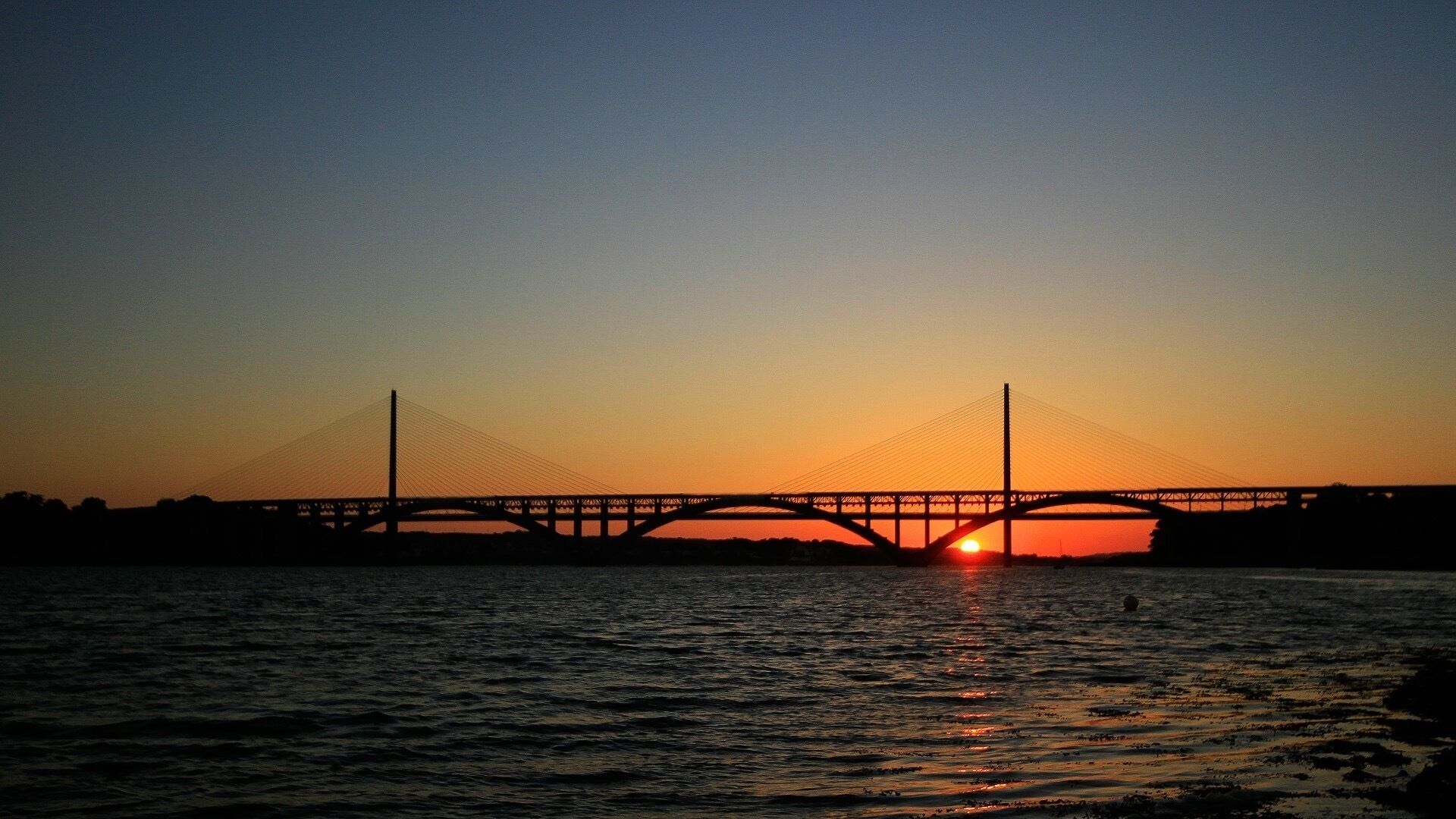 A bridge at sunset with the sun setting behind it.