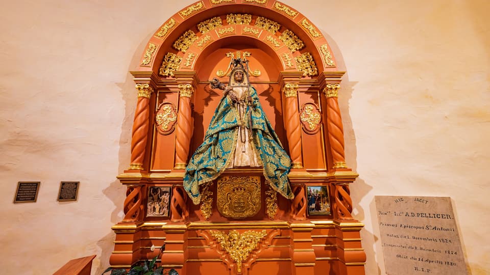 A statue with a blue and gold robe, a golden crown, and a plaque with inscriptions.