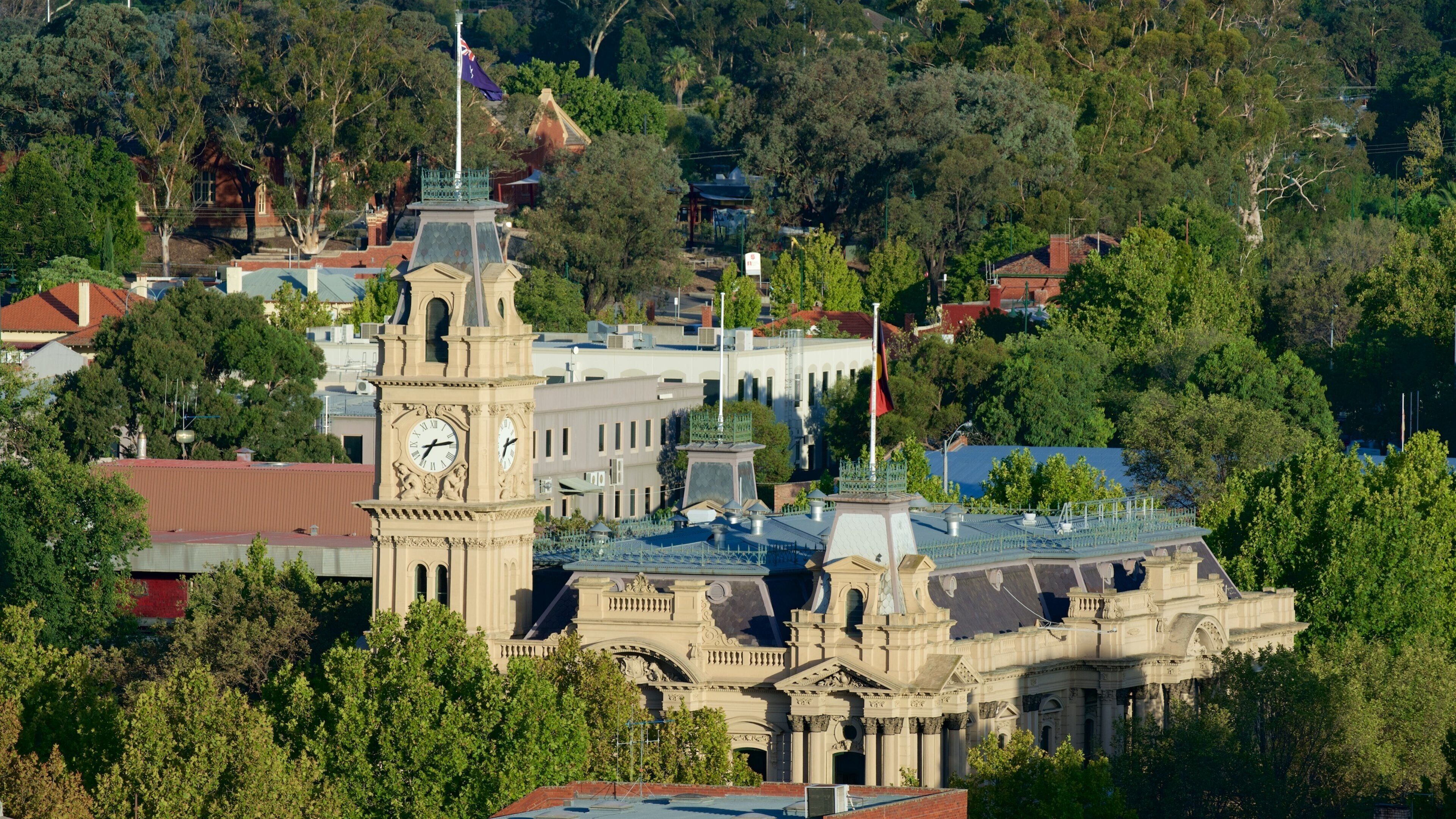 A historic building with a clock tower, surrounded by lush greenery and other structures.