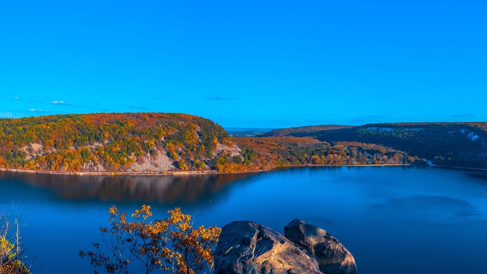 A lake surrounded by autumn-colored trees and rocky terrain.