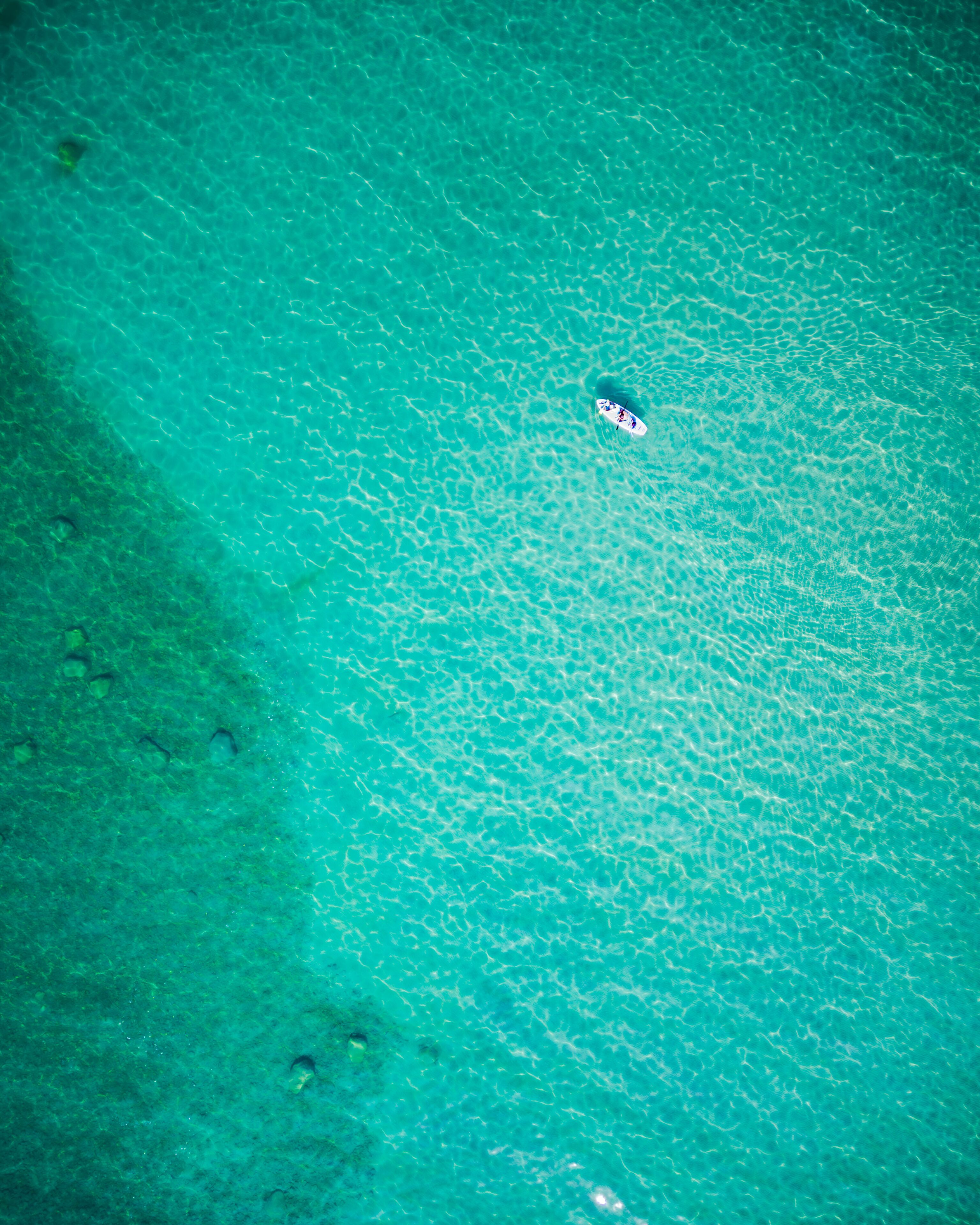 Paddle boarder in Lake Huron, vivid turquoise waters from above