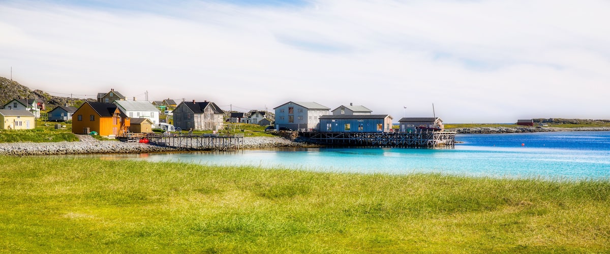 A coastal village with houses, a pier, and a calm blue sea.