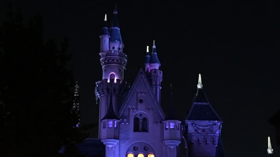 A castle-like structure with multiple towers and arched windows, illuminated at night.