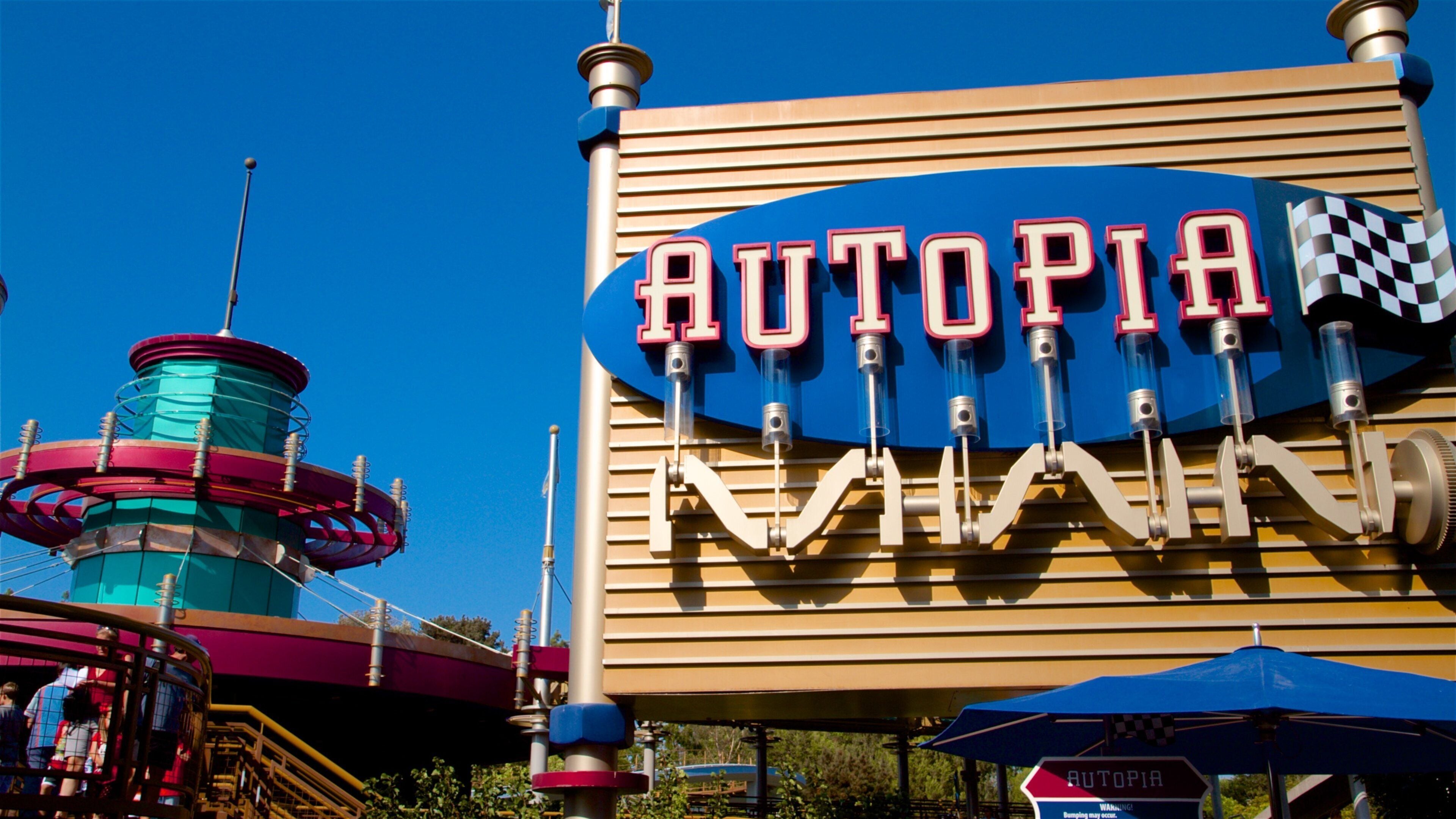A sign for Autopia Raceway with a checkered flag and a roller coaster in the background.