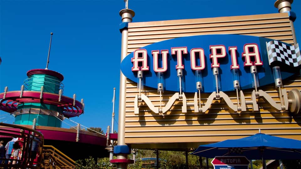 A sign for Autopia Raceway with a checkered flag and a roller coaster in the background.