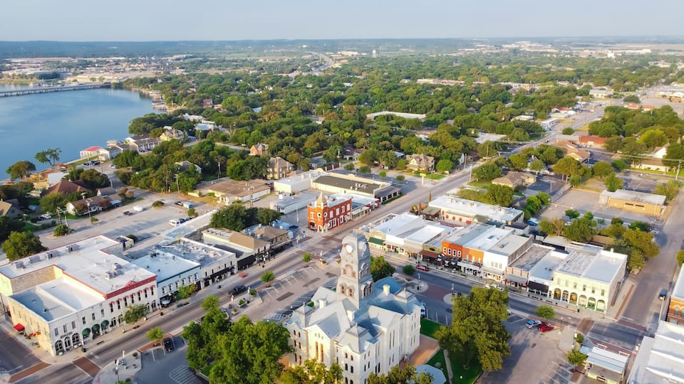 An aerial view of a town with a river, green spaces, and historic buildings.