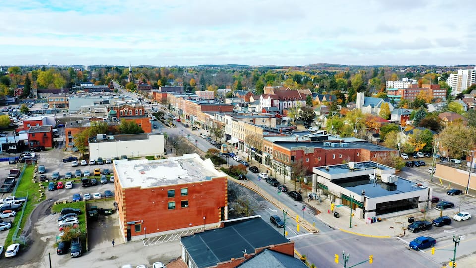 A cityscape with a mix of historic and modern buildings, a parking lot, and a river in the background.