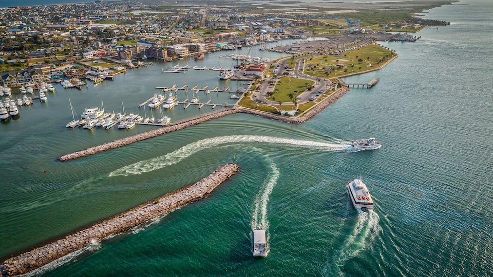 A coastal city with a marina, boats, and a breakwater.