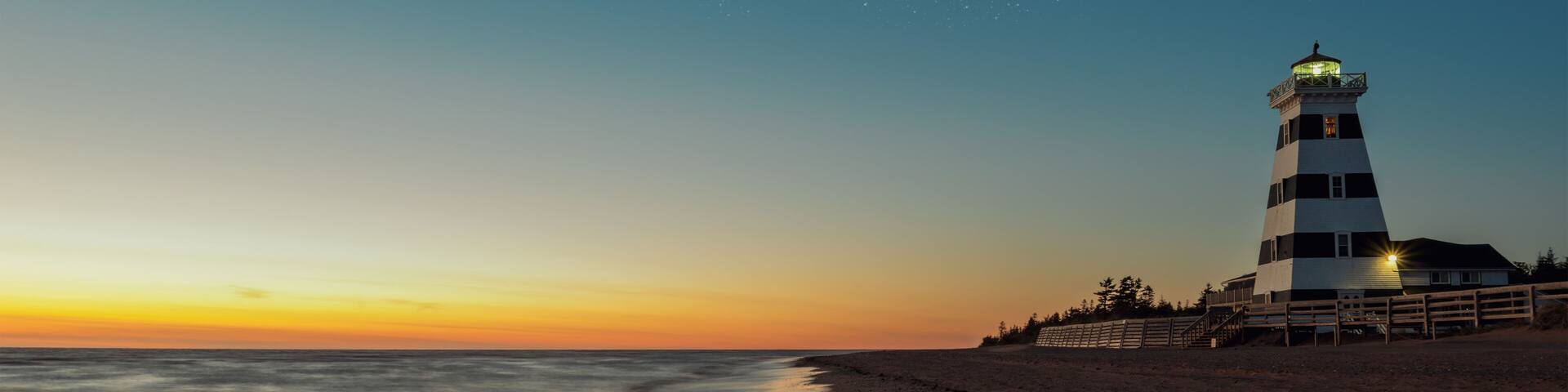 A lighthouse at sunset with a starry sky.