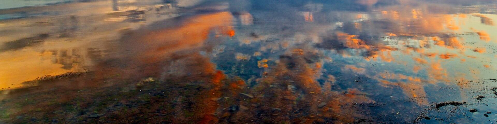 A dramatic sunset reflected in mirror calm waters of Maria, Baie des Chaleurs , Gaspesie in Quebec, Canada