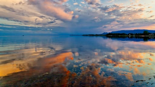A dramatic sunset reflected in mirror calm waters of Maria, Baie des Chaleurs , Gaspesie in Quebec, Canada
