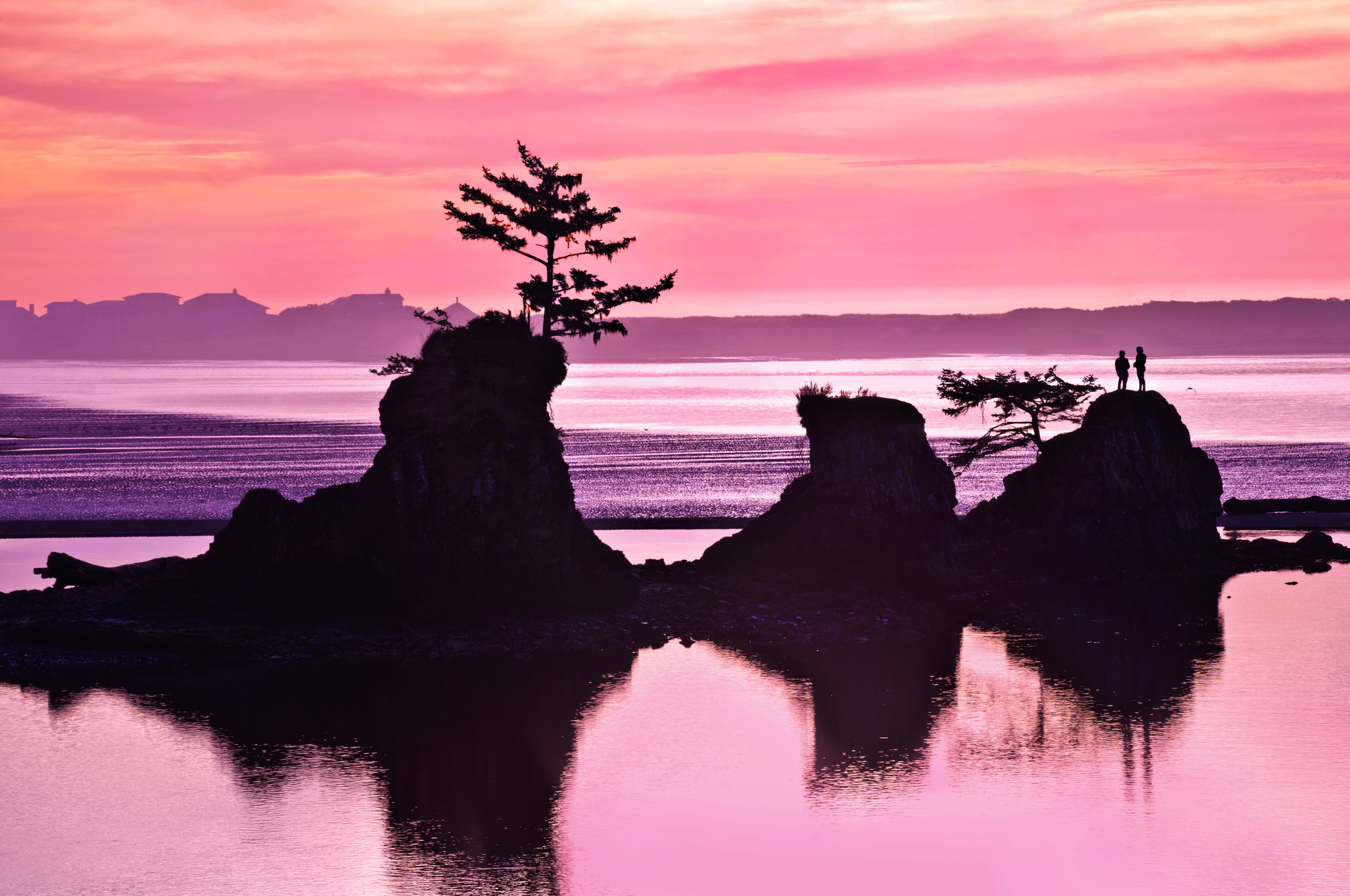 Sunset of Beach with rock formations and pink and purple tones of light/Sunset of pink and purple colors on beach in Siletz Bay, Oregon with silhouettes of rock and hiker