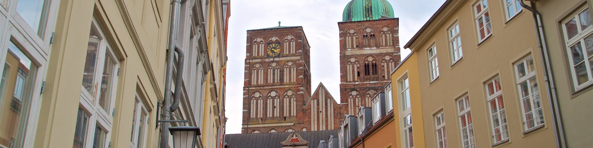 Una calle estrecha con edificios coloridos, una iglesia con aguja verde y una torre del reloj.