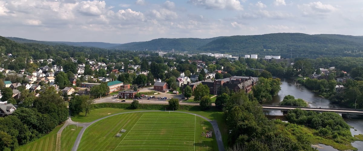 A town with a river, a bridge, and a football field.